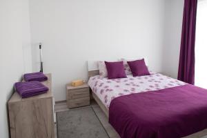 ein Schlafzimmer mit einem Bett mit lila Bettwäsche und lila Kissen in der Unterkunft Apartament Lila in Sibiu