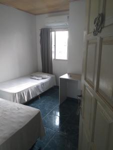 a small room with two beds and a window at Hotel Raiz in Manaus