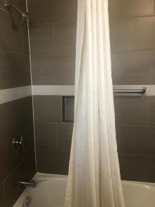 a bathroom with a white shower curtain and a tub at Robinhood Motel in Anaheim