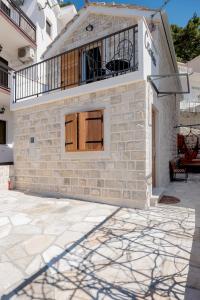a brick house with a balcony and a patio at Apartment Cesarica in Baška Voda