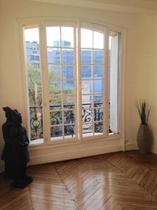 パリにあるAppartement typiquement parisienのバルコニー付きの大きな窓が備わる客室です。