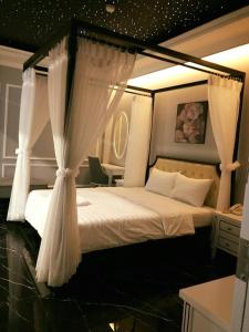 a bedroom with a canopy bed with white curtains at La Galerie Hotel in Ho Chi Minh City