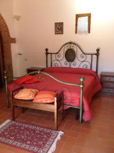 a bedroom with a bed with a red blanket and a bench at Agriturismo Torrevecchia in Pienza