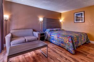 a bedroom with a bed and a chair and a table at Siesta Motel in Nogales