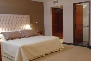 a bedroom with a large white bed with a large headboard at Hotel de la Cañada in Córdoba
