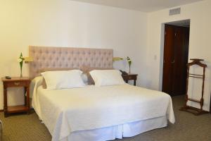 a bedroom with a large white bed with two pillows at Hotel de la Cañada in Córdoba
