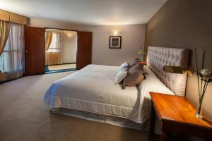 a bedroom with a large white bed and a table at Hotel de la Cañada in Córdoba