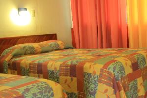 two beds in a hotel room with orange curtains at Hotel Avenida in Acapulco