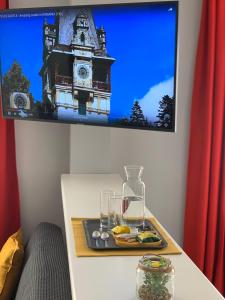 un tavolo con un piatto di cibo e un orologio su una TV di Vila De Argint a Sinaia