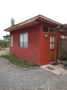 una casa rossa con una porta davanti di Cabañita Totoverde a El Totoral