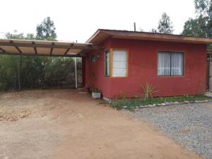 una casa rossa con un posto auto coperto davanti di Cabañita Totoverde a El Totoral