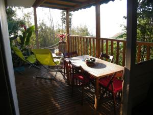 a porch with a table and chairs on a deck at LES HAUTS DE FALAISE in Bouillante