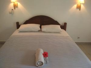 a bed with two towels and a red flower on it at ALMAIDA II Gili Trawangan in Gili Trawangan