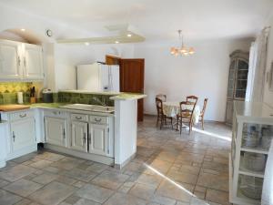 Una cocina con gabinetes blancos y una mesa y sillas. en Villa Le Bouloulou by Interhome, en Velleron