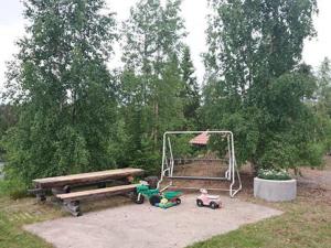 a park with a bench and a swing and toys at Holiday Home Käkiharju by Interhome in Sulkava