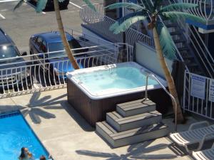 bañera de hidromasaje junto a una piscina con palmeras en Quarterdeck Motel, en Wildwood