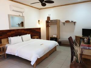 a bedroom with a large white bed and a desk at Liquid Dive Resort in Dauin