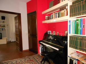 a room with a piano and a red wall at B&B Come A Casa in Cerrione