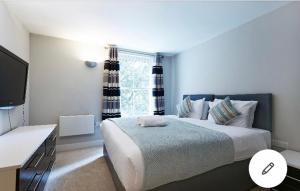 a bedroom with a large bed and a television at Copperfield Apartment in Canterbury
