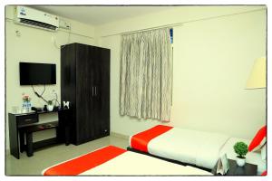 班加罗尔Orange Corner, Near Kempegowda Airport, Airport Pickup And Drop Available 24x7的一间卧室配有一张床、一个橱柜和一台电视