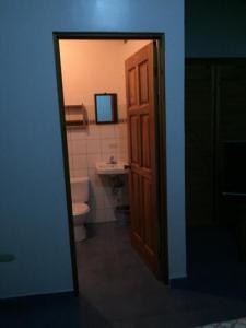 een badkamer met een toilet, een wastafel en een deur bij Cabinas Lindo Horizonte in San Pedro