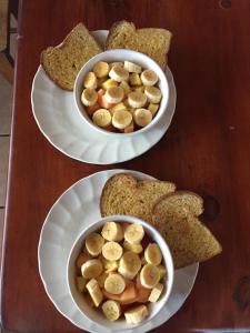 dos platos blancos con dos cuencos de plátanos y pan en Cabinas Lindo Horizonte, en San Pedro