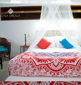 1 dormitorio con 1 cama con colcha roja y blanca en Casa Dibulla Hotel Boutique en Dibulla