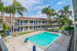 a swimming pool in front of a building with palm trees at Motel 6-Bakersfield, CA - Airport in Bakersfield