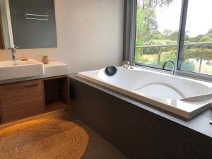 uma casa de banho com uma banheira, um lavatório e uma janela em Messmates Luxury Eco Suites em Inverloch