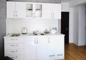 a white kitchen with a sink and white cabinets at Stela Apartments in Obzor