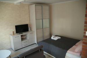 Schlafzimmer mit einem Bett und einer Kommode mit einem TV in der Unterkunft ALIBI Apartament Boleslawiec in Bolesławiec