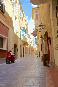 a red scooter parked on a street in an alley at Cosy Haven, 96 Triq il-Karita', Victoria Gozo in Victoria