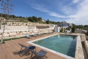 a swimming pool with chairs and a house at Madre in Ragusa