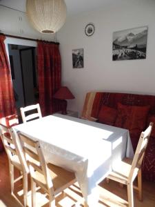 ラ・ノルマにあるappartement tous confortのベッド付きの客室で、白いテーブルと椅子が備わります。