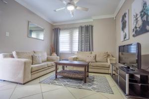 a living room with a couch and a tv at Three Oaks and an Aloe Boutique Hotel in Hartbeespoort