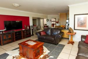 a living room with leather furniture and a flat screen tv at Tranquil Shores in Wilderness