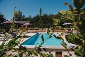 a swimming pool with tables and umbrellas at Les Olivades in Gap