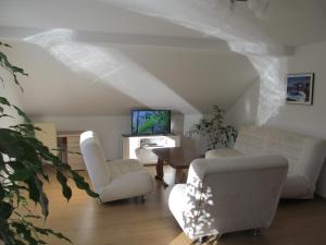a living room with white furniture and a tv at Natasa Apartments in Jezerce