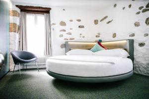 a bedroom with a large white bed and a chair at Hotel Murtenhof & Krone in Murten