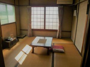 um quarto com uma mesa em frente a uma janela em Kofuji Ryokan em Kurashiki