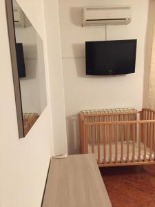 a room with a crib and a tv on the wall at Residenza Longobardi in Vibonati
