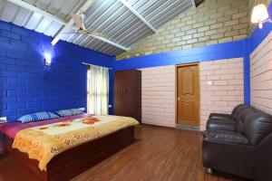 a blue bedroom with a bed and a leather couch at Rustling River Resort in Ooty