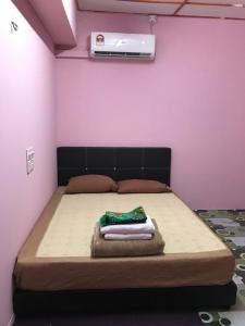 a bed in a room with a pink wall at langkawi homestay murah in Kuah