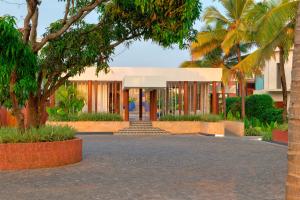 a building with palm trees in front of it at Azaya Beach Resort Goa in Benaulim