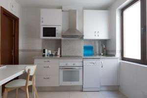 a kitchen with white cabinets and a table and a chair at APARTAMENTOS OASIS in Zamora