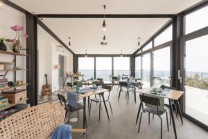 uma sala de jantar com mesas e cadeiras e janelas grandes em Madre em Ragusa