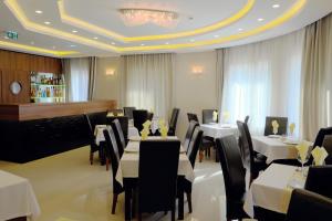 ein Restaurant mit weißen Tischen und Stühlen und einem Kronleuchter in der Unterkunft Vácz Hotel in Vác