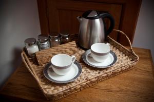 a basket with two cups and saucers on a table at Lugonia in Pitlochry