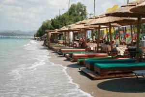 ein Strand mit vielen Liegestühlen und Sonnenschirmen und dem Meer in der Unterkunft Mousonette in Selínia