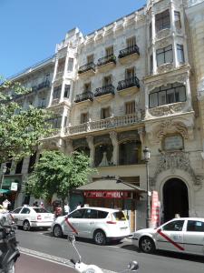 un gran edificio con coches estacionados frente a él en Hostal Mayor en Madrid